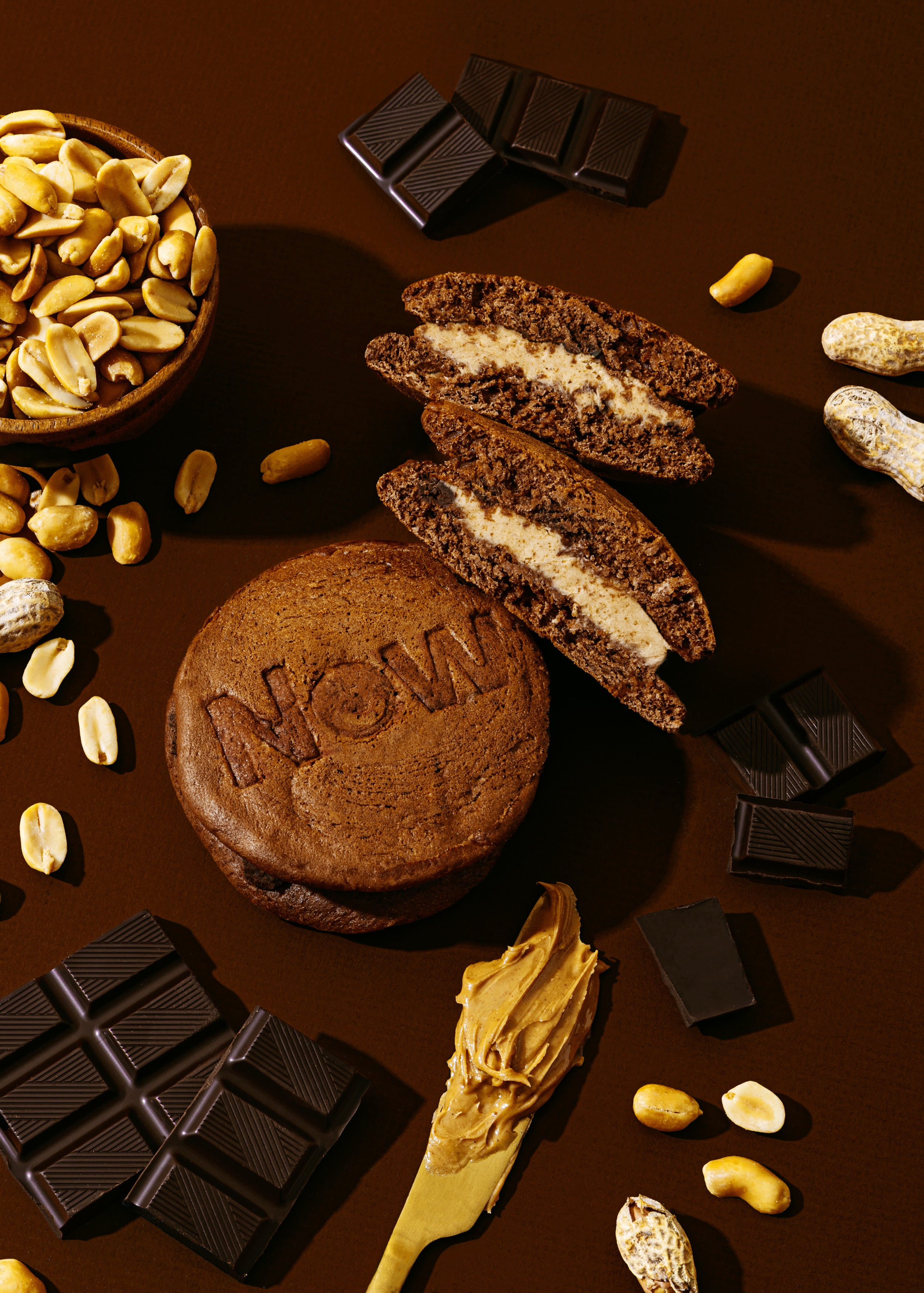 Chocolate Pancake Sandwich with Peanut Butter filling, chocolate bars, and nuts on a brown background