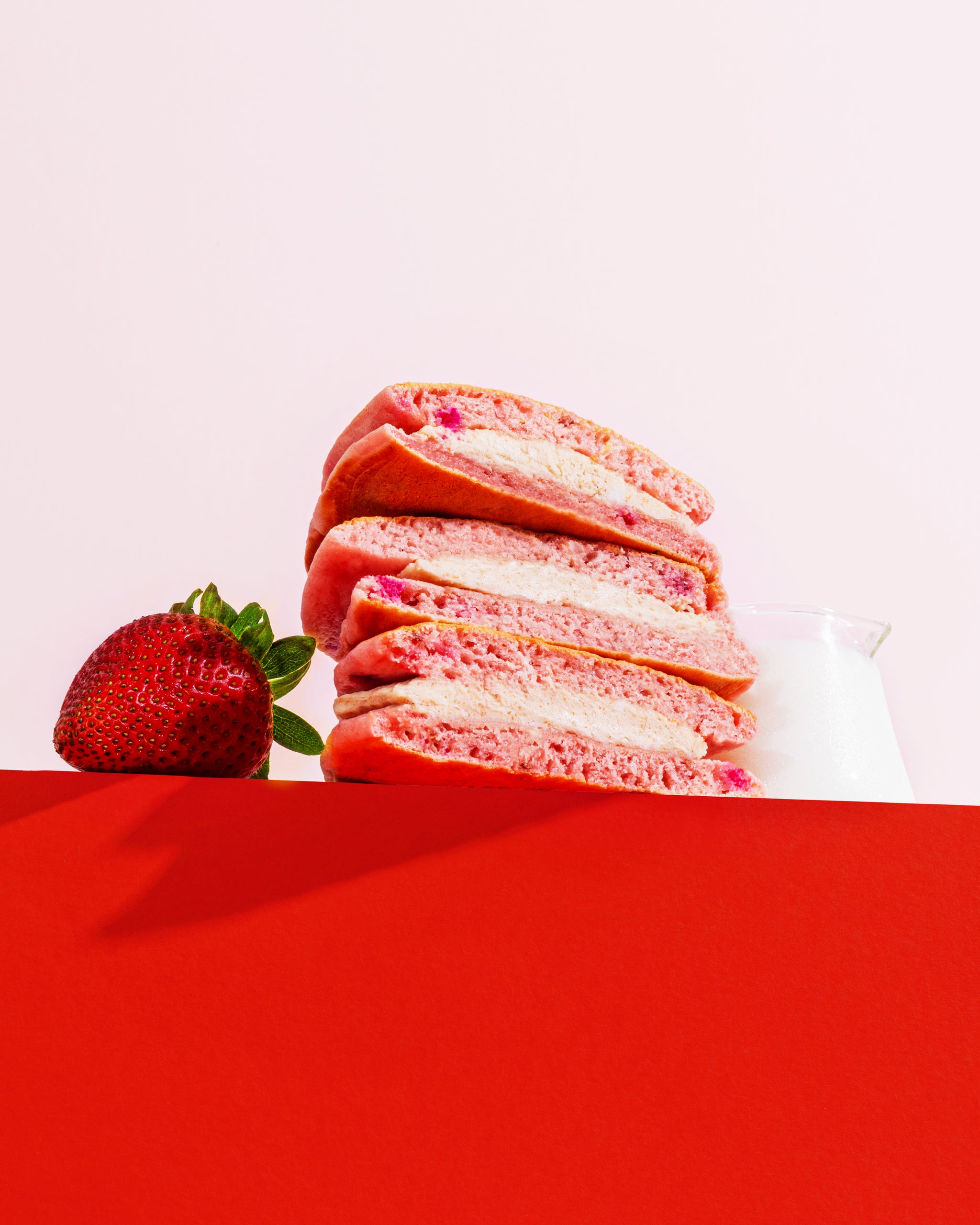 Strawberry & Cream Pancake Sandwich Stacked with a strawberry next to it.